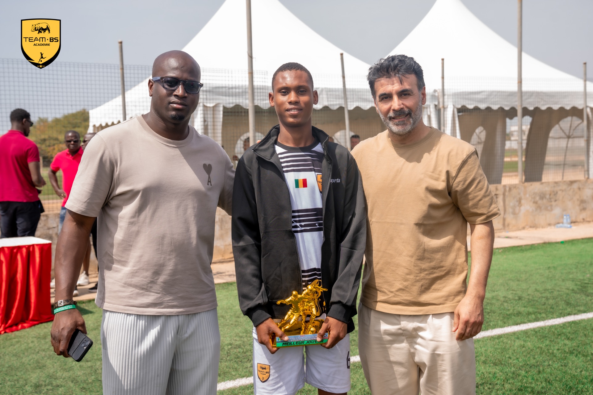 Morel avec son trophée de meilleur joueur du tournoi, entouré de deux accompagnateurs
